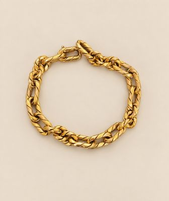 un bracelet en or orné d'une corde torsadée sur fond beige