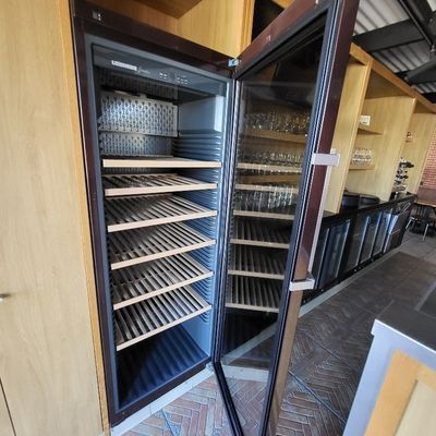 un réfrigérateur ouvert contenant de nombreuses étagères remplies de bouteilles de vin