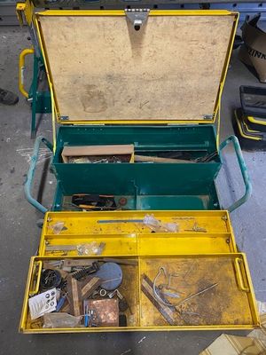 une boîte à outils jaune posée par terre, contenant des outils