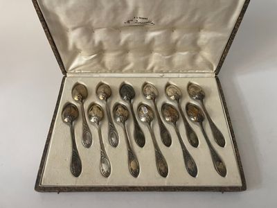 six cuillères dans un étui en argent posé sur une table blanche