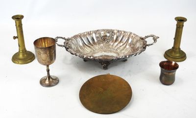 un bol en argent et d'autres objets en laiton posés sur une surface blanche