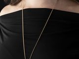 the woman is wearing a black top and a gold necklace