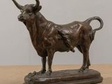 bronze statue of a bull on a wooden base on a table