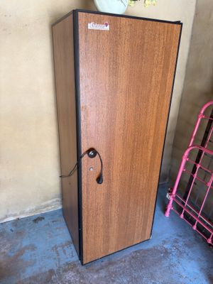 une armoire en bois munie d'une porte, devant laquelle se trouve une étagère rose