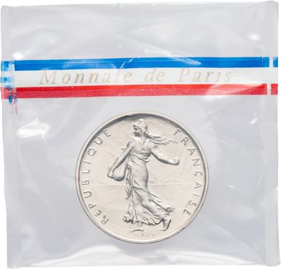 un gros plan d'une pièce de monnaie dans un sachet en plastique sur fond blanc