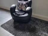 a black chair with a pillow on it in front of a window