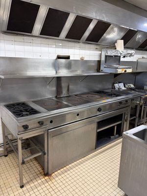 une grande cuisine professionnelle équipée d'appareils électroménagers et de plans de travail en acier inoxydable