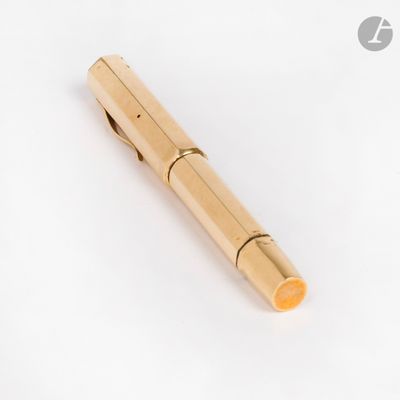le stylo doré repose sur une surface blanche, devant un fond blanc