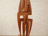 a wooden sculpture on a wooden table with a white wall in the background