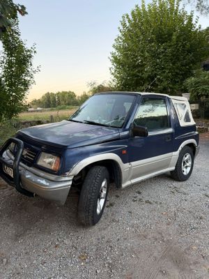 une photo d'un SUV bleu garé sur un parking en gravier