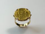 Gros plan sur une bague en or ornée d'une pièce de monnaie
