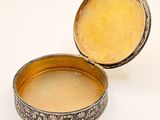 an old silver box with a lid on a white surface