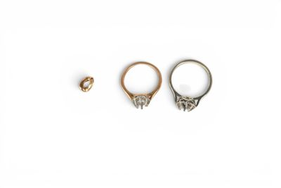 two gold rings and a silver ring on a white background