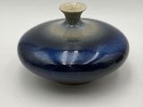 a small blue vase with a gold top on a white surface