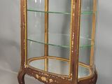 une vitrine ancienne avec des étagères en verre et des finitions dorées