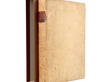 an old book with a brown cover sitting on top of a white surface