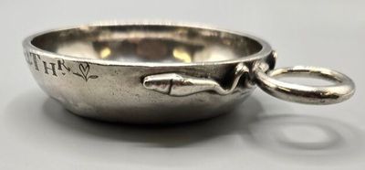 un bol en argent orné d'un poisson, posé sur une table