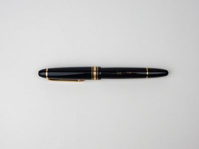 un stylo noir et or posé sur une surface blanche