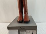 une paire de bottes marron posée sur une boîte, elle-même posée sur un lit