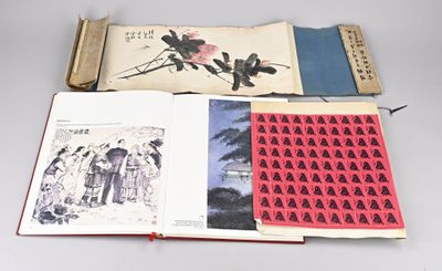 un livre ouvert posé sur une table blanche, à côté d'un livre rouge