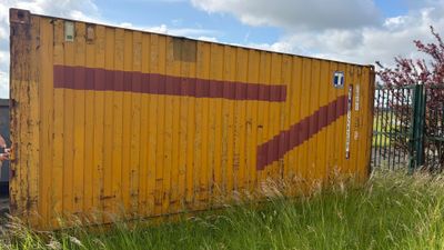 un conteneur jaune sur lequel est peinte une flèche rouge sur le côté