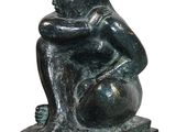 statue of a woman sitting on a ball with her hands on her knees