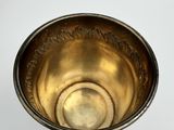 a silver bowl with a gold rim sitting on a white surface