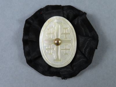 a black and white brooch with a gold button on it