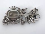 a silver brooch with a horse and carriage on it