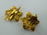 a pair of gold plated metal flowers on a white surface