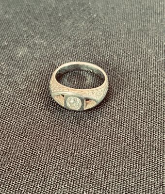 une bague en argent avec une pierre au centre, posée sur un tissu
