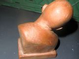 une petite sculpture en bois représentant une personne assise sur une table