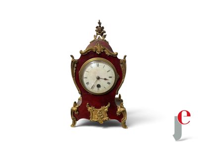 a small red and gold clock sitting on a white surface