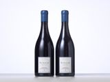 two bottles of red wine sitting next to each other on a table