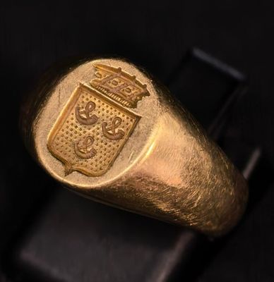 un gros plan d'une bague en or sur laquelle est gravé un blason