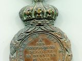 une vieille médaille en bronze surmontée d'une couronne
