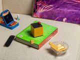 a picture of a book, a remote control, and a box on a couch
