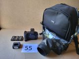 un sac à dos, un appareil photo, des piles et d'autres objets disposés sur une table