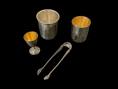 trois tasses en argent et une cuillère sur fond noir