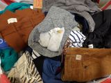 a basket full of clothes and a purse on a bed