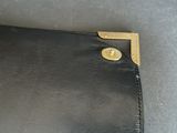 a black leather wallet with a gold button on it