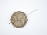a silver coin with a pin in it on a white surface