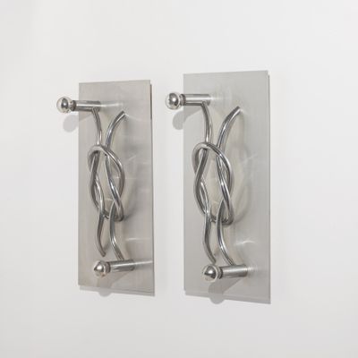deux crochets métalliques fixés à un mur, avec un mur blanc en arrière-plan