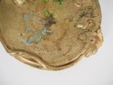 a gold plate with a bird on it on a table