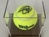 une balle de tennis jaune dans une boîte transparente posée sur une table