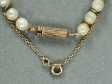 un gros plan sur un collier orné de perles et muni d'un fermoir en or