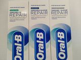 three toothpaste tubes sitting on top of a table next to each other