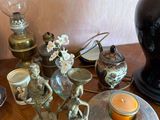 a table with a lamp, vase, candle holder, and other items on it