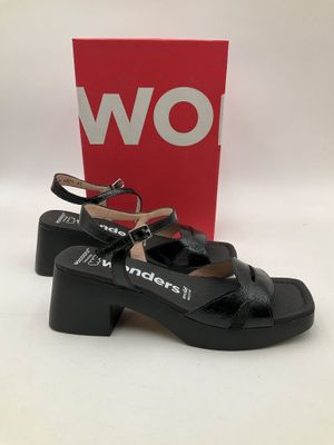 une paire de sandales noires pour femme, avec une boîte rouge en arrière-plan