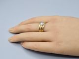 bague en or jaune sertie d'un diamant, au doigt d'une femme